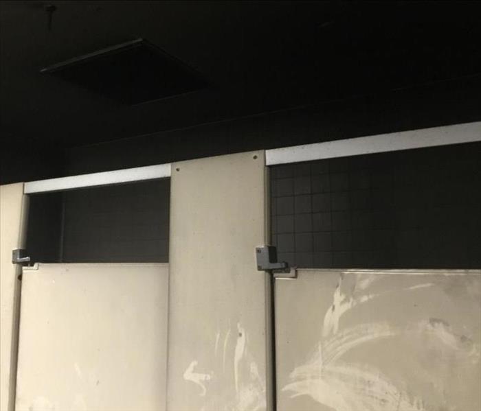 Bathroom stalls and ceiling covered in heavy, black soot